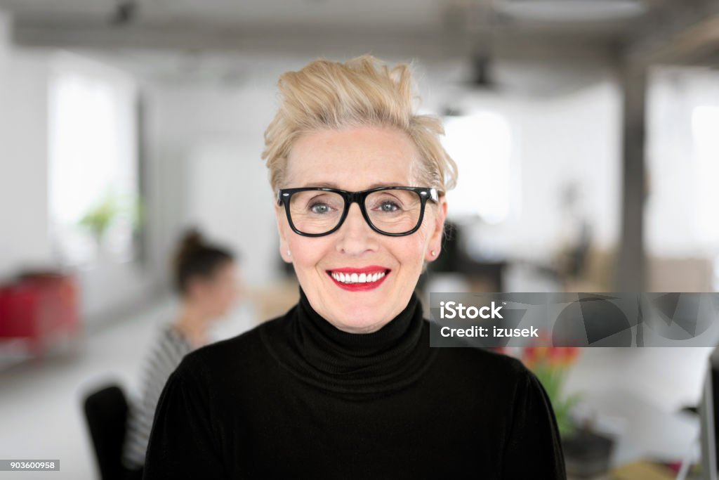 Portrait of elegant senior businesswoman in the studio Portrait of elegant senior businesswoman standing in her office, smiling at the camera. Close up of face. Eyeglasses Stock Photo
