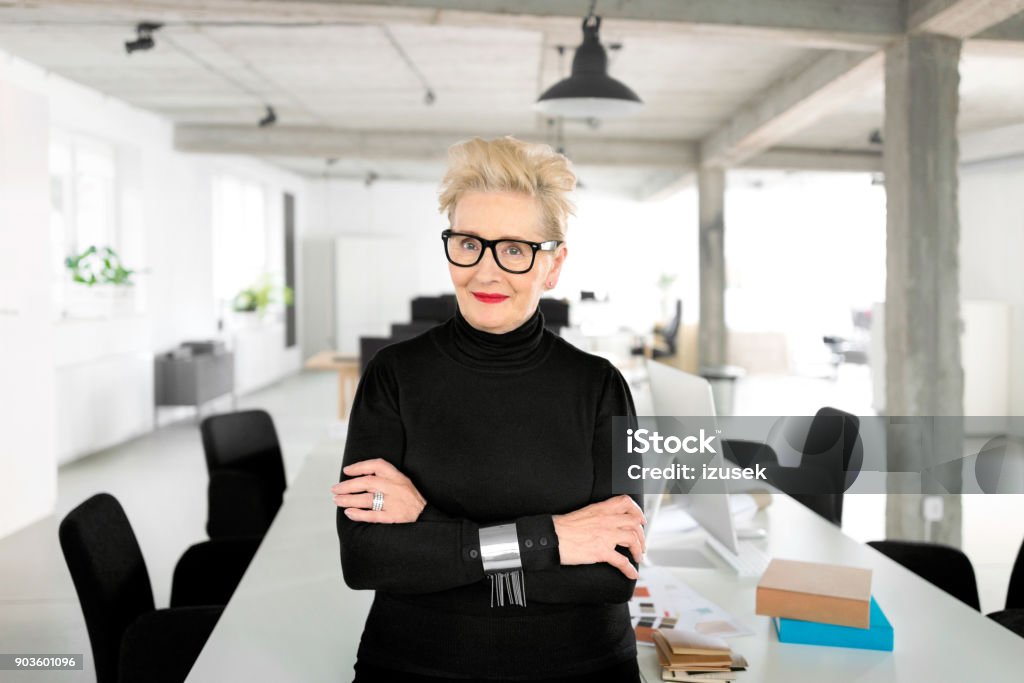 Confident senior businesswoman in the studio Portrait of senior elegant businesswoman standing in her office, smiling at the camera. Smiling Stock Photo