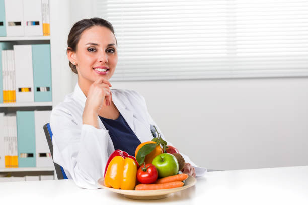 Female dietician showing vegetables and fruit stock photo