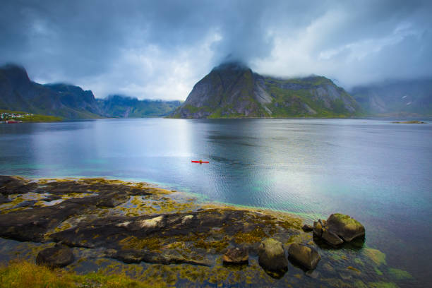 Autumn norway scene, Reine. Small red kayak in bay on Lofoten islands, Norway.