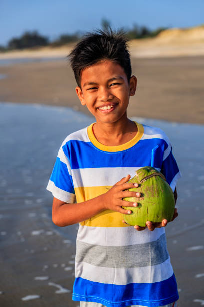 Vietnamese boy holding coconuts on the beach, Vietnam