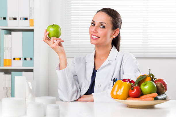 istock Female nutritionist holding a green apple 903606674