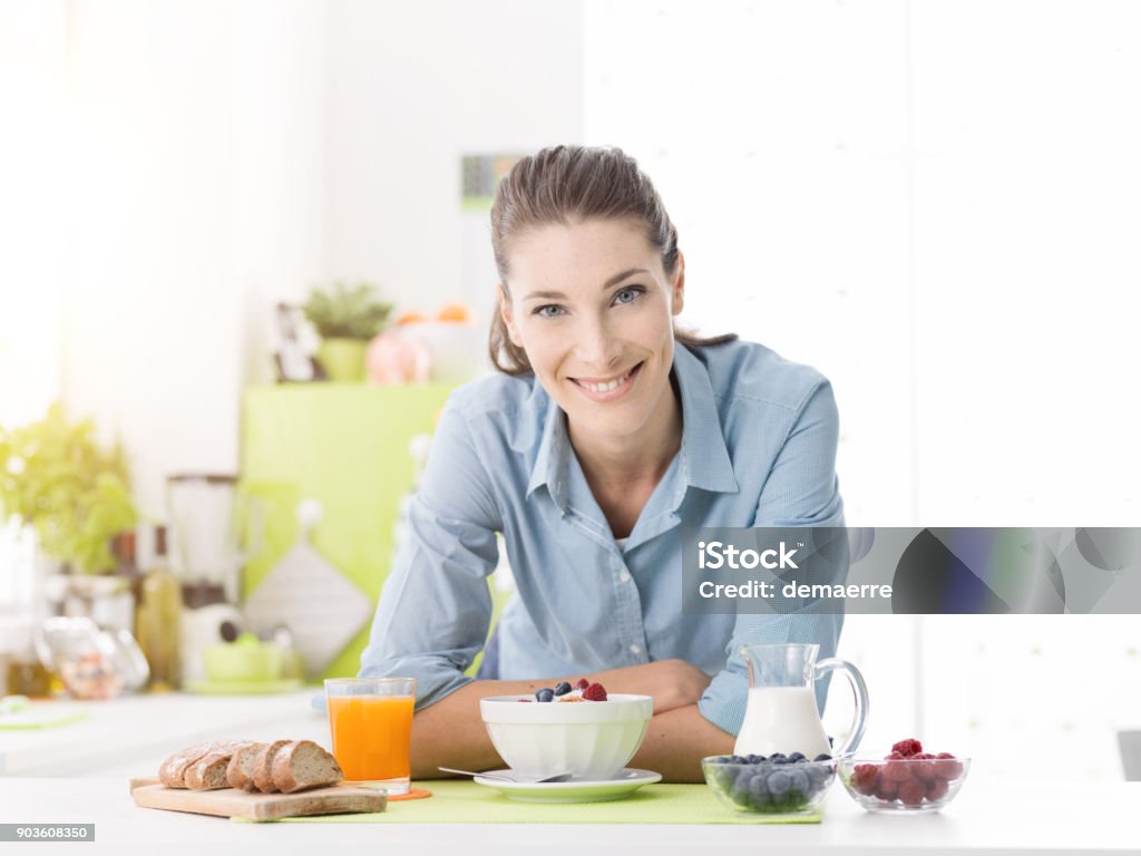 Femme souriante prenant son petit déjeuner à la maison - Photo de Nutritionniste libre de droits