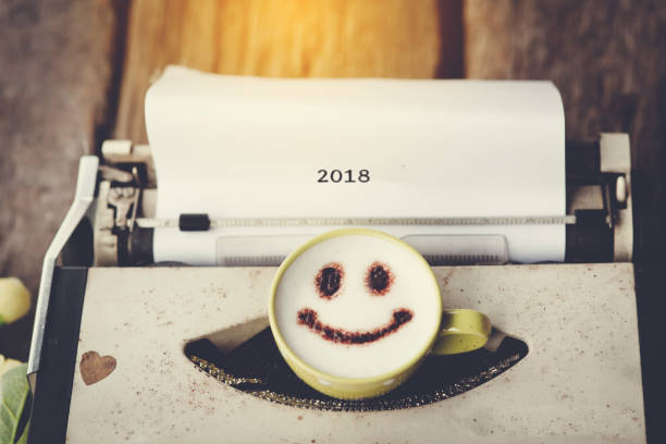 istock Typewriter with happy face coffee cup with blurry message 2018, sepia tone. 903609110