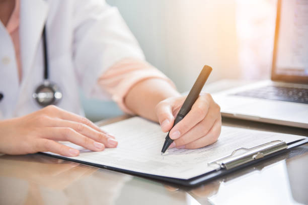 istock female doctor is using laptop and writing something on clipboard. 903609684