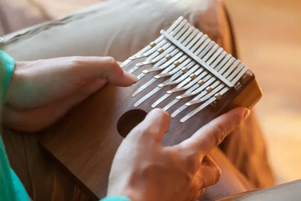 Man holding traditional African musical instrument large kalimba in one's hands. Man playing on the kalimba