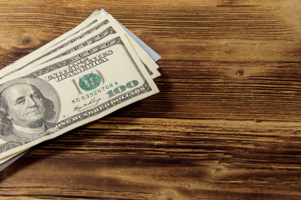 istock Stack of one hundred dollars bills on wooden desk 903613446