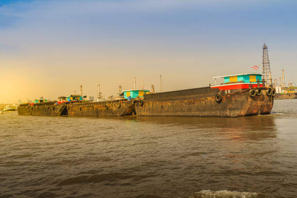 istock Small tugboat is pulling a large shipping barge up the Chao Phraya River in Bangkok, Thailand. 903616432