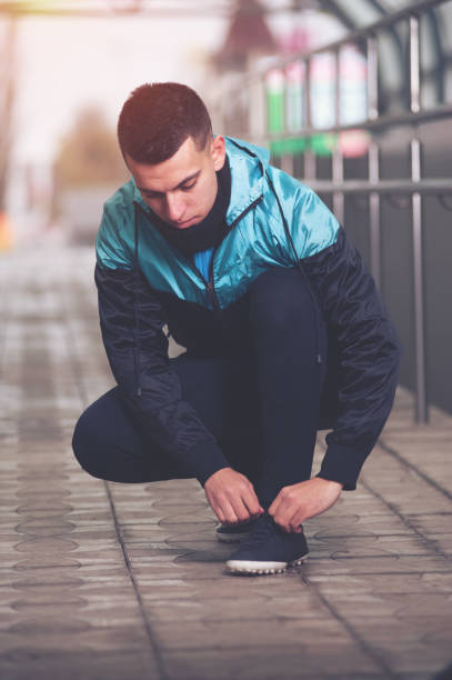 istock Handsome young man tying shoe laces. 903616448