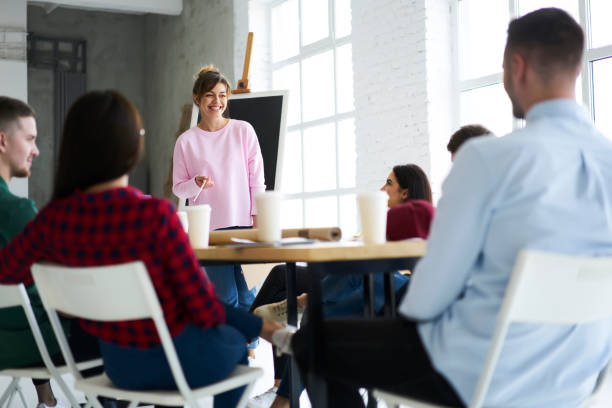 istock Cheerful professional female business coach making workshop for students of university talking about successful strategies for startup, speaker explaining to journalists concept of informal meeting 903623962