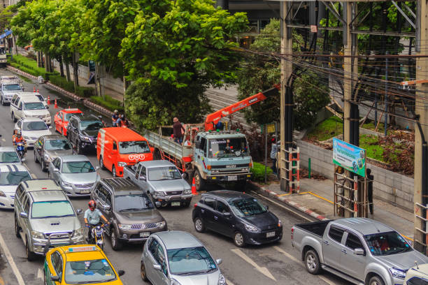 Bangkok, Thailand - April 1, 2017: Truck loader crane is lifting big roadside tree causing traffic jammed in the rush hour.