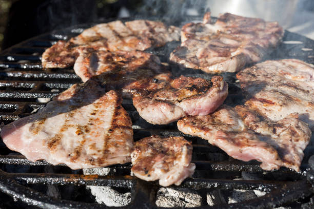 istock Grilling pork chops with delicious toasted traces. Smoke. Close up view 903625656
