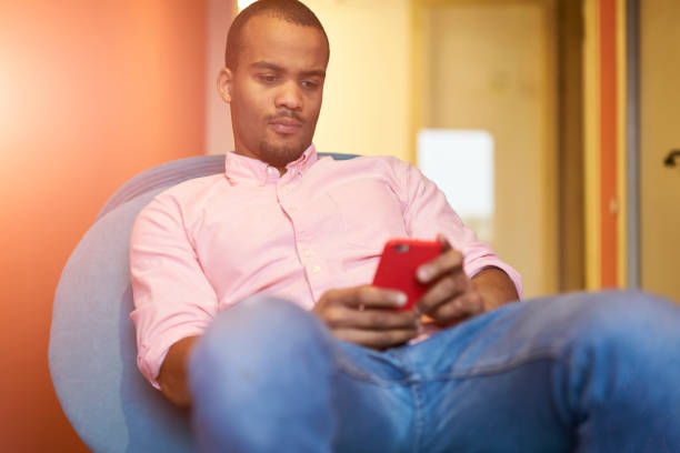 Confident creative businessman watching interesting video on internet and messaging with partners on telephone during work break,young hipster guy reading news on cellular using 4G wireless connection