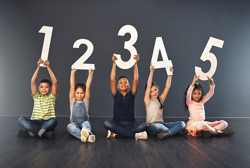 Studio portrait of a diverse group of kids holding up numbers against a gray background