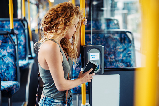Commuting and traveling by public transportation in big city. Woman with curly hair using commuter contactless payment method for commuting