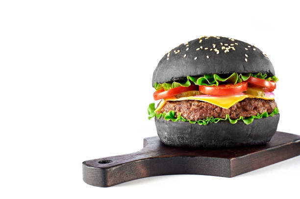 istock Black burger on wooden cutting board isolated on white background. 903636234