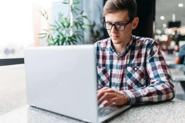 istock A man sits in a cafe and working on laptop, looking for work, the student writes the homework, a guy in a shirt and glasses 903641406