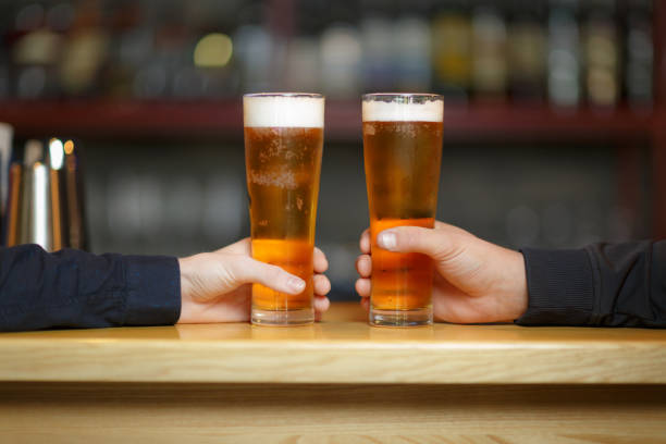 istock Two men's hands hold two glasses with a beer. 903648724