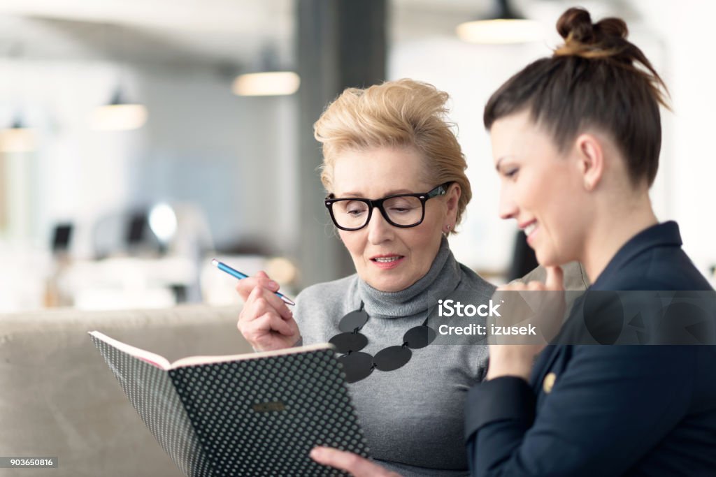 Senior adviser talking with young businesswoman Senior woman talking with young businesswoman, giving advices. Business Stock Photo