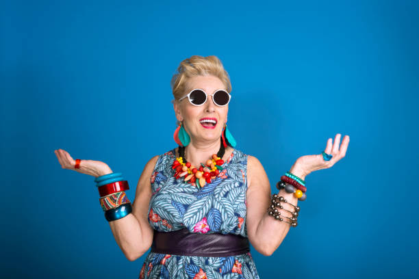 Summer portrait of creative senior woman Summer portrait of creative, colorful senior woman against blue background. Studio shot. middle aged woman fashion stock pictures, royalty-free photos & images