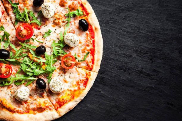 istock Hot pizza slice with melted mozzarella cheese and tomato on black concrete background.  Pizza Ready to Eat, Copyspace.