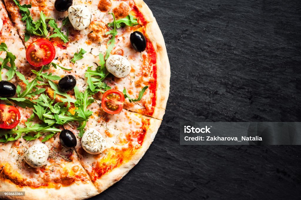 Hot pizza slice with melted mozzarella cheese and tomato on black concrete background.  Pizza Ready to Eat, Copyspace."n Pizza Stock Photo