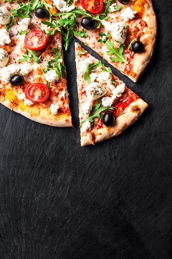 Hot pizza slice with melted mozzarella cheese and tomato on black concrete background.  Pizza Ready to Eat, Copyspace.