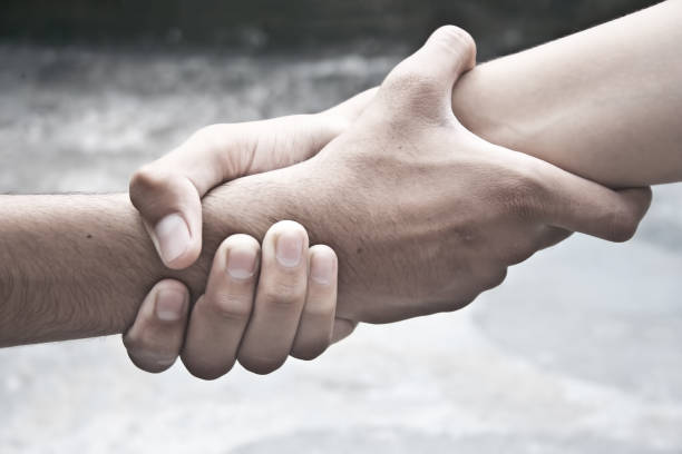 istock One human hand helping another hand to overcome his fear. 903670260