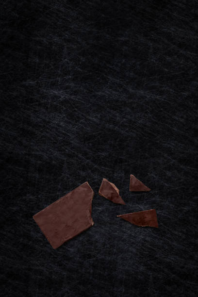 istock Top view of a broken dark chocolate bar isolated on a scratched slate chopping board. 903672040
