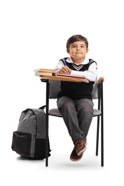 Group of kids in a classroom with a happy boy raising hand during lesson in the elementary school