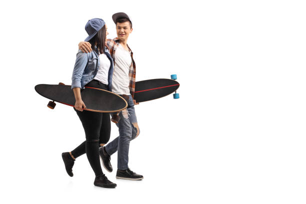 Full length profile shot of teenage skaters with longboards talking with each other and walking isolated on white background