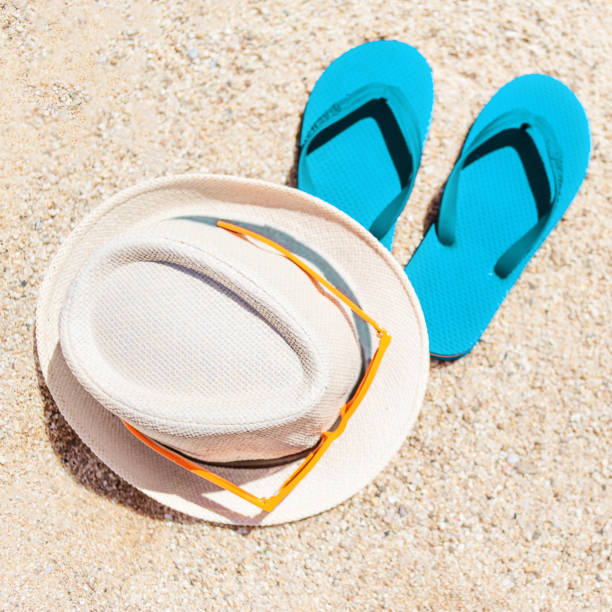 istock Summer holiday beach background with flip flops and hat  on a tropical beach. Slippers on a  sand with copyspace 903680464