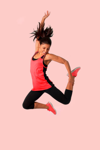 young attractive and happy Latin sport woman jumping excited and cheerful in gym exercise workout healthy lifestyle and freedom concept isolated on clear background with studio light stock photo