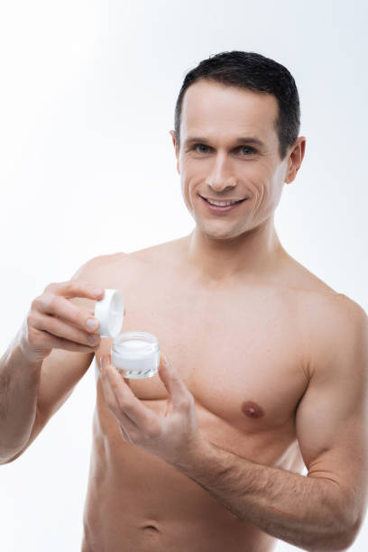 attraente uomo ben costruito che ti mostra crema per il corpo - men smooth the human body moisturizer foto e immagini stock