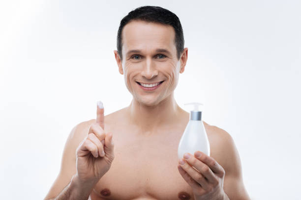 gioioso uomo felice usando la lozione del corpo - men smooth the human body moisturizer foto e immagini stock