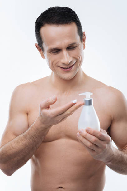 uomo felice e attraente usando la lozione del corpo - men smooth the human body moisturizer foto e immagini stock