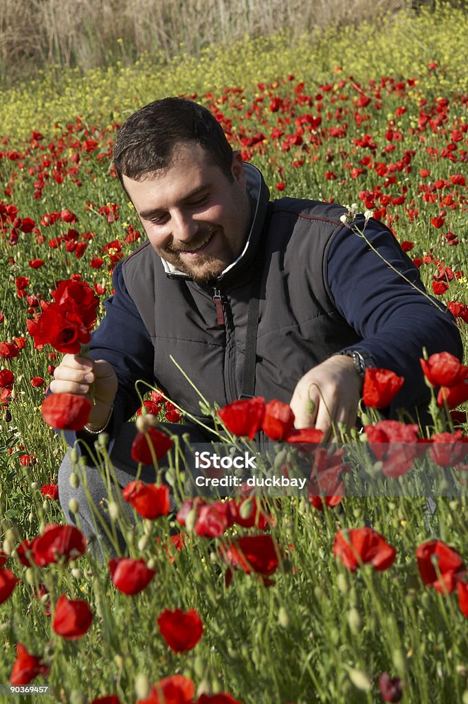 Hombre joven en un campo de amapolas - Foto de stock de Aire libre libre de derechos