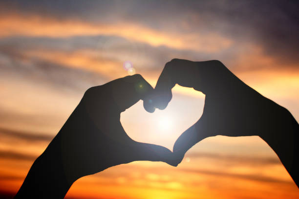 istock Close-Up Of Silhouette Hand Making Heart Shape Against Sky During Sunset 903694812