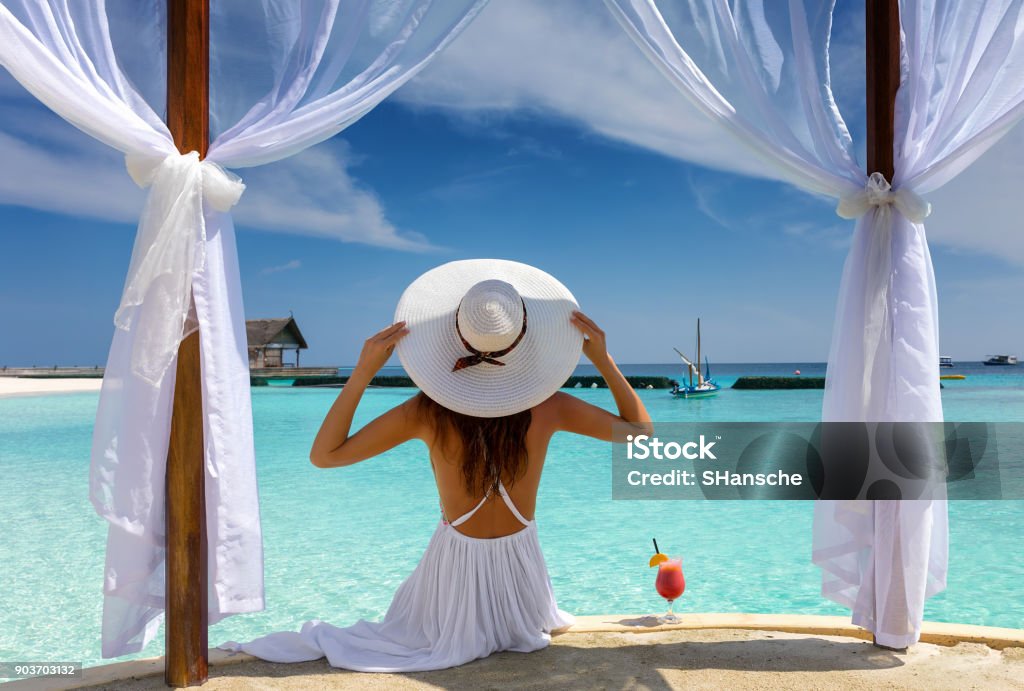 Beautiful woman enjoys her summer holiday in the tropics Beautiful woman with white hat enjoys her summer holiday in the tropics Beach Stock Photo