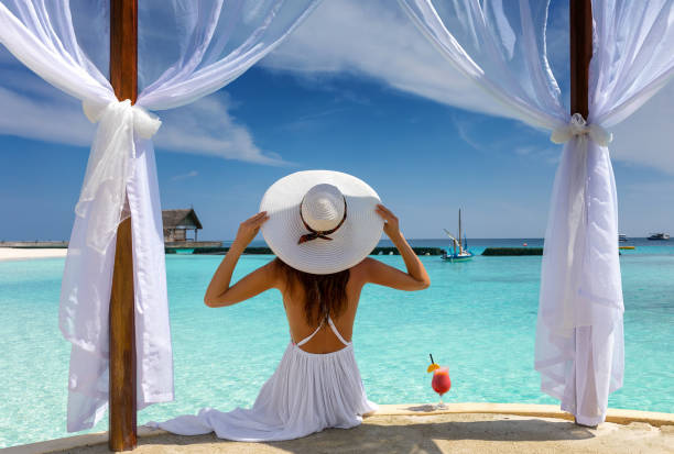 Beautiful woman enjoys her summer holiday in the tropics Beautiful woman with white hat enjoys her summer holiday in the tropics beach fashion stock pictures, royalty-free photos & images