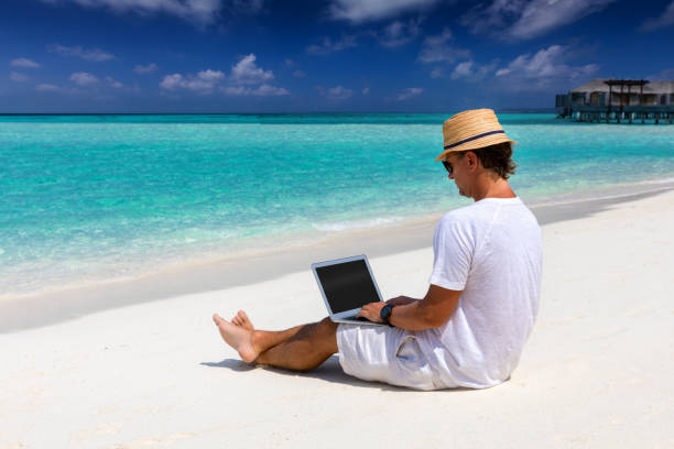 istock Man sits on a tropical beach with his laptop 903707416