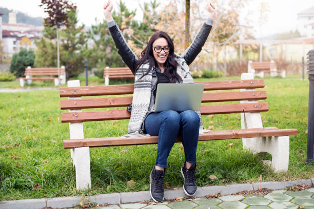 istock Euphoric young woman with a laptop 903708164