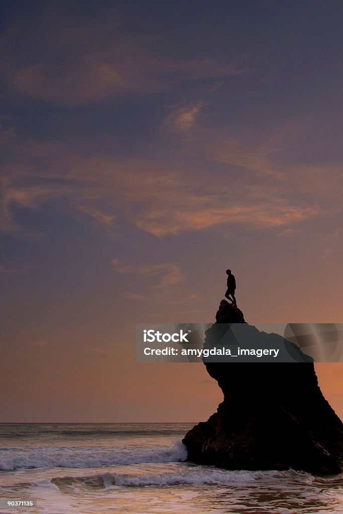 silueta hombre de pie en la cima rocosa del atardecer mar - Foto de stock de Acantilado libre de derechos