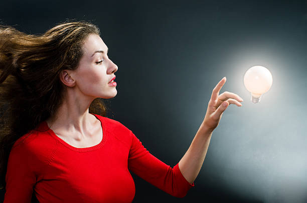 istock Woman reaching out to touch an illuminated light bulb 90371779