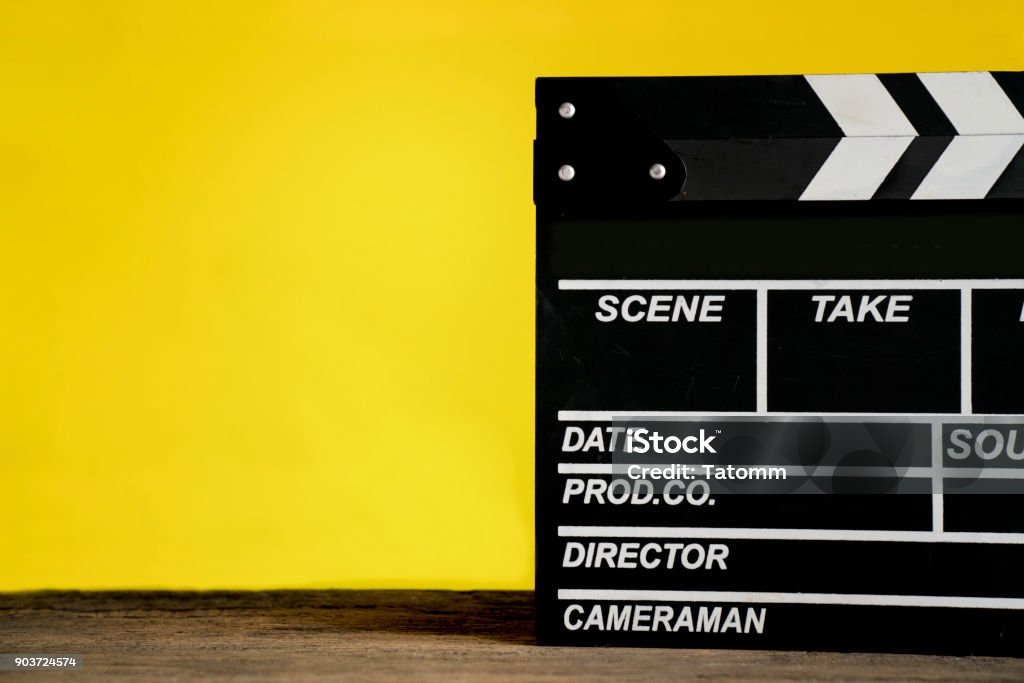 movie clapper on wood table with yellow background ; film, cinema and video photography concept Home Video Camera Stock Photo