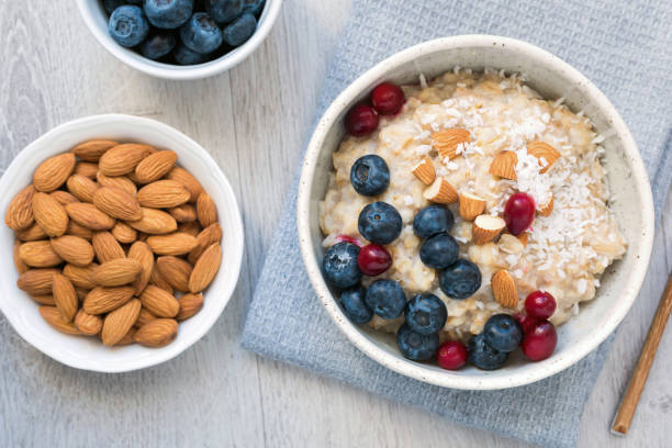 istock Oatmeal porridge with berry and nuts in white bowl. Table top view 903731484