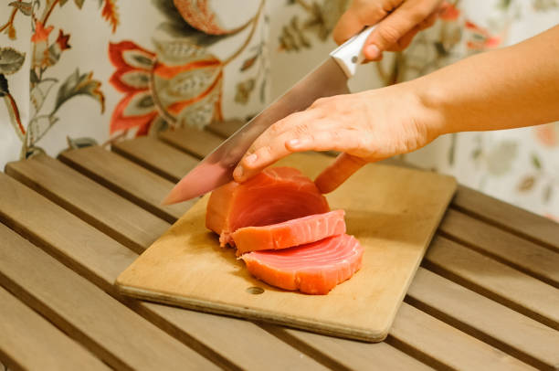 Woman cutting fresh salmon fillet on wooden board