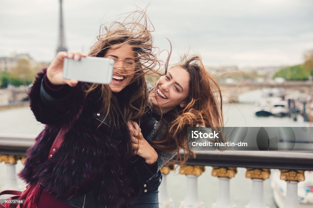 Girls enjoying vacation in Paris Young women in Paris taking selfie against the Seine river Travel Stock Photo