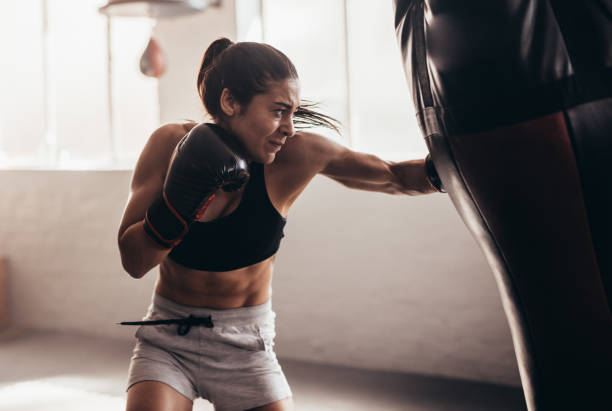Female boxer training inside a boxing ring Female boxer hitting a huge punching bag at a boxing studio. Woman boxer training hard. martial arts stock pictures, royalty-free photos & images