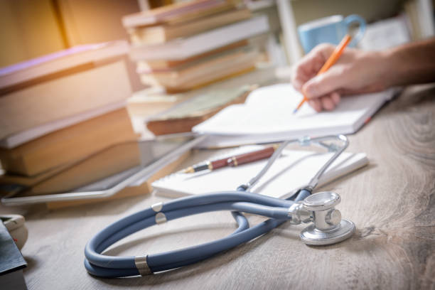 Doctor is preparing for the exam Young doctor is learning and preparing for the exam, he is using books and tablet to search for knowledge doctor utensils stock pictures, royalty-free photos & images